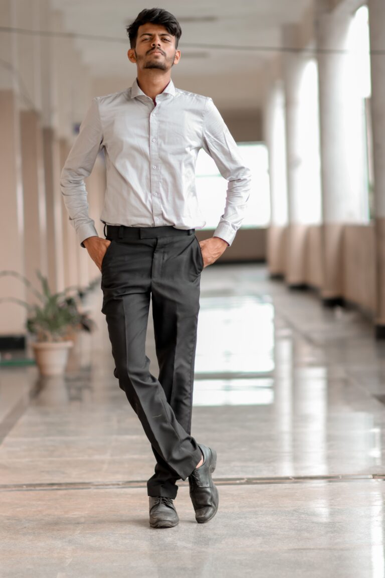 A confident man in formal attire posing in a bright hallway.